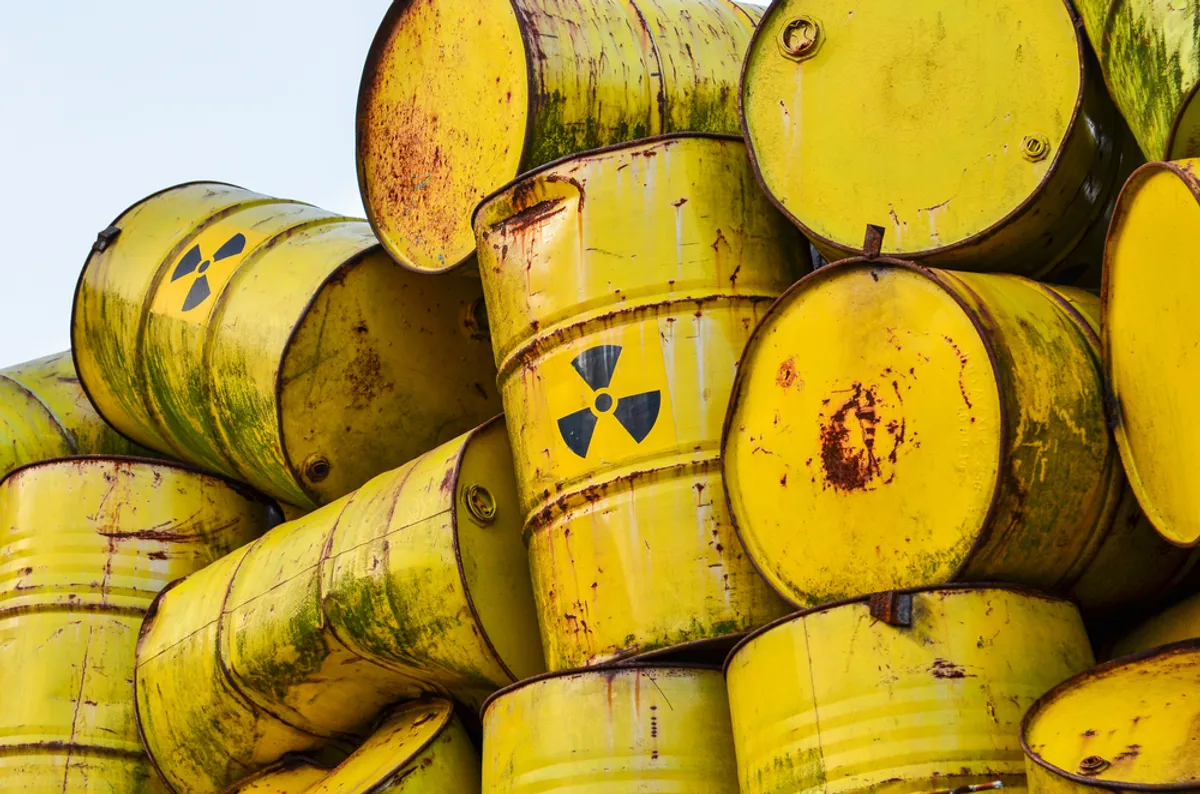 A large pile of empty yellow barrels with radioactivity warning labels.